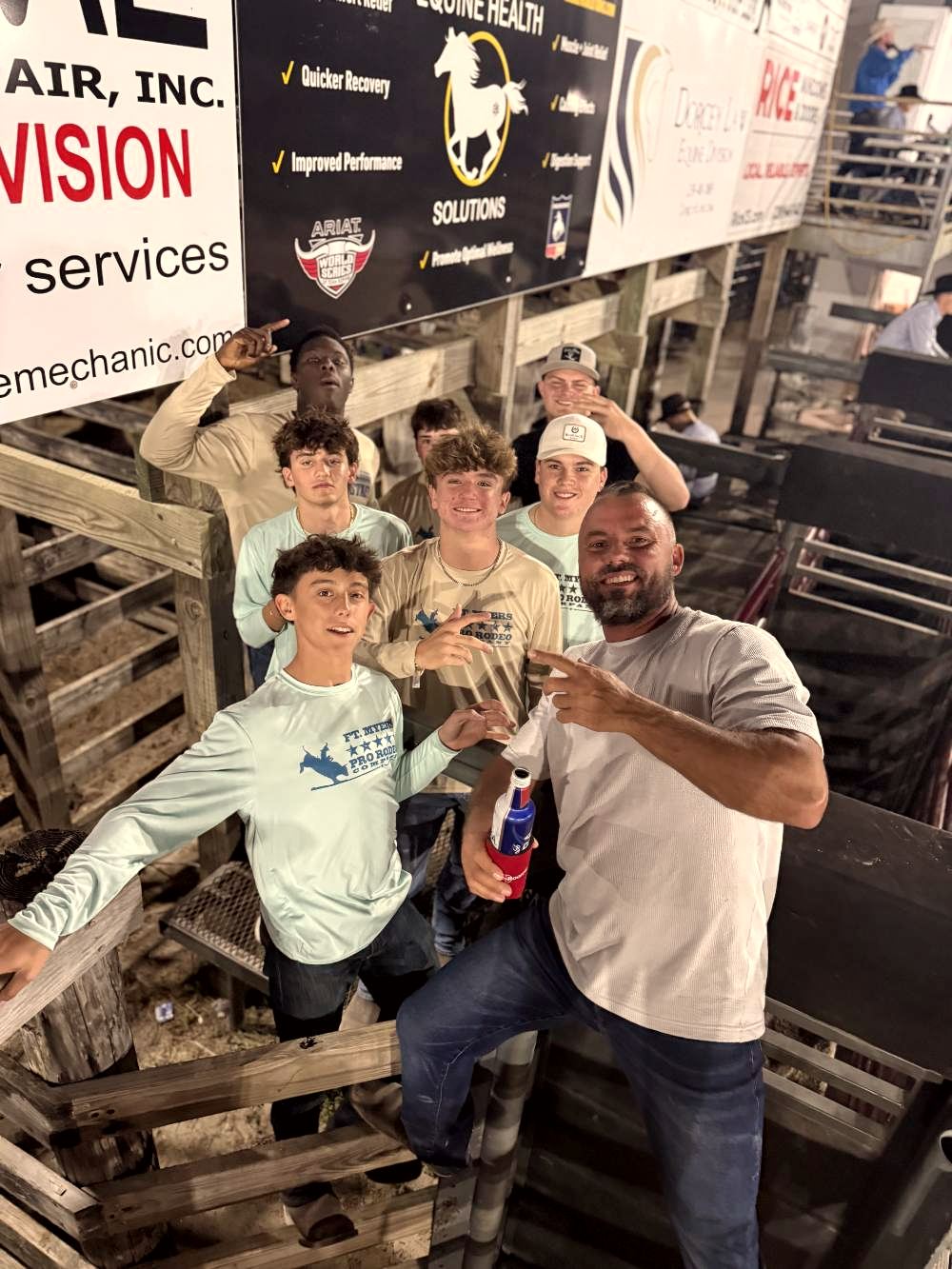 Rodeo volunteers and young people by the sponsor banners
