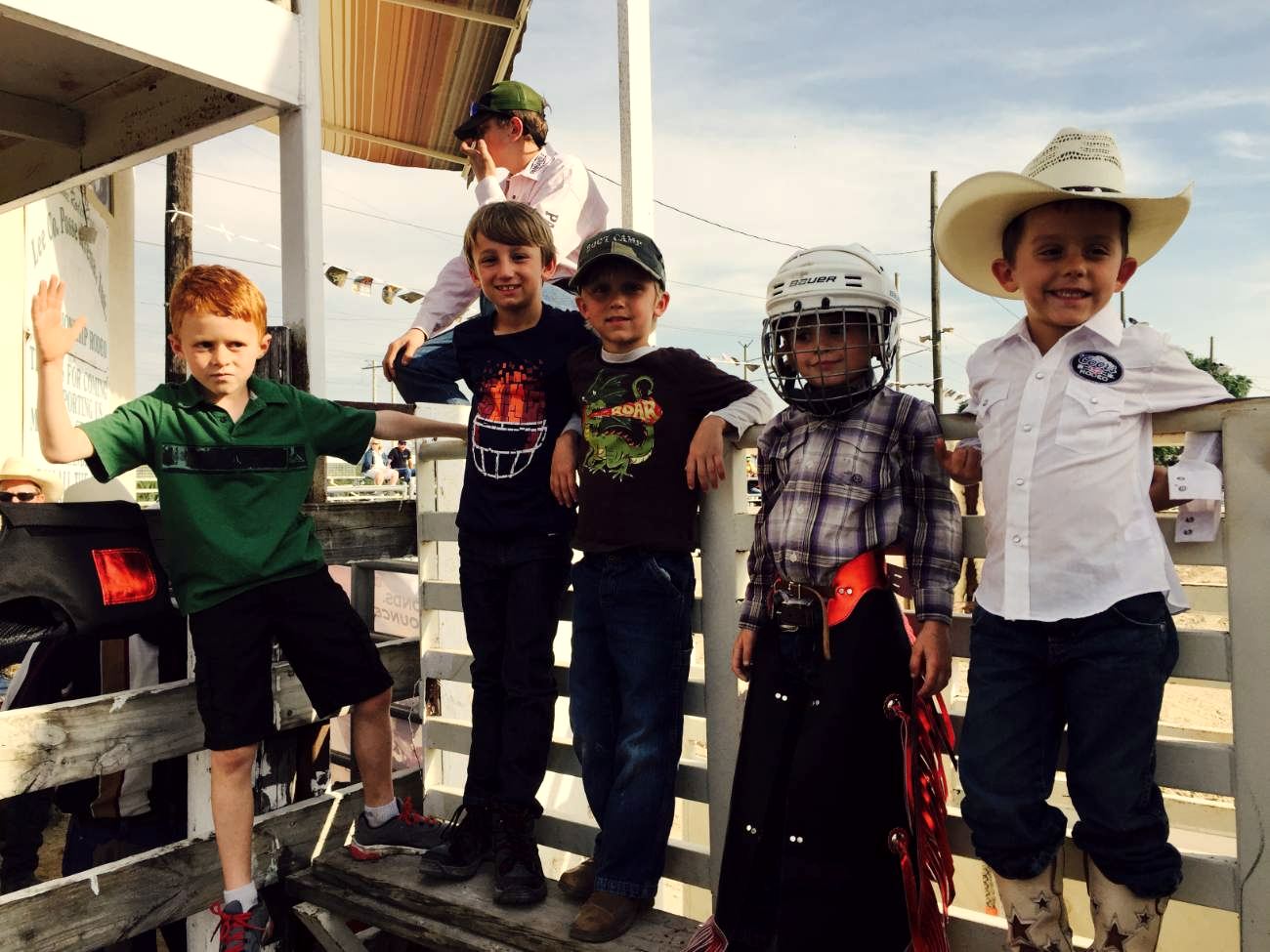 Five young rodeo riders gathered beside the arena chutes
